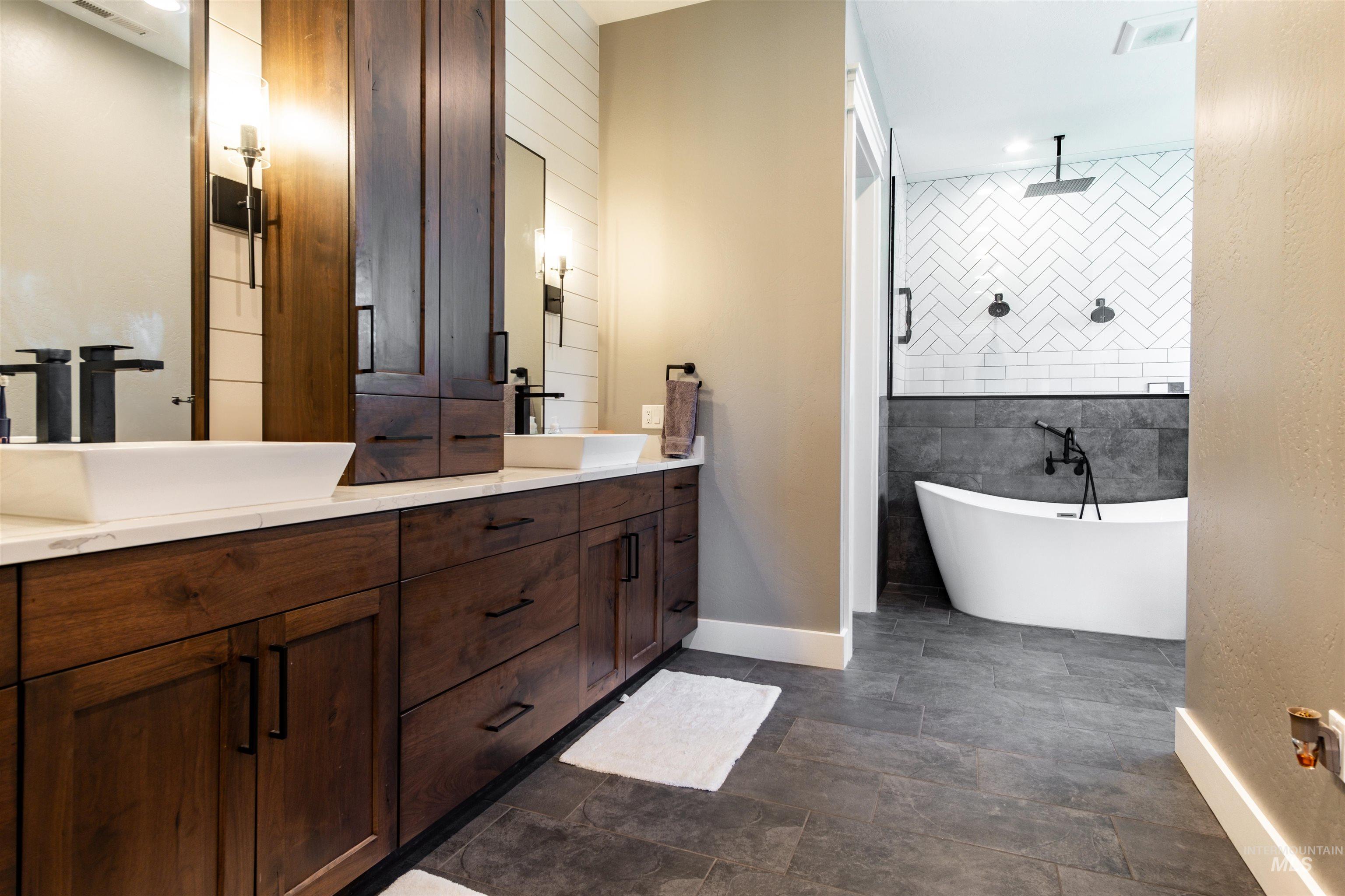 Full bath with double vanity, a soaking tub, and a tile shower