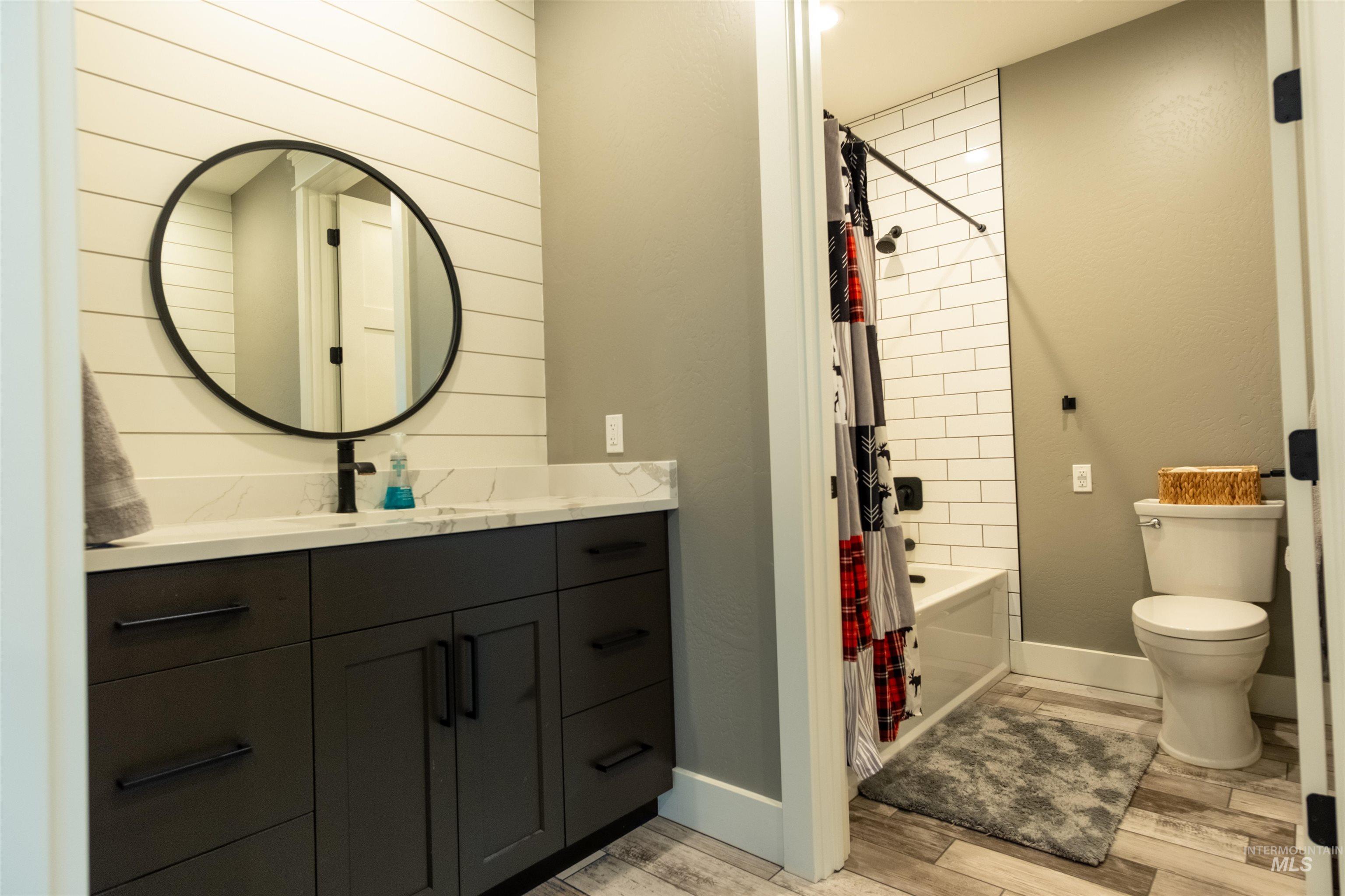 Bathroom with vanity, wood finished floors, and shower / bath combo with shower curtain