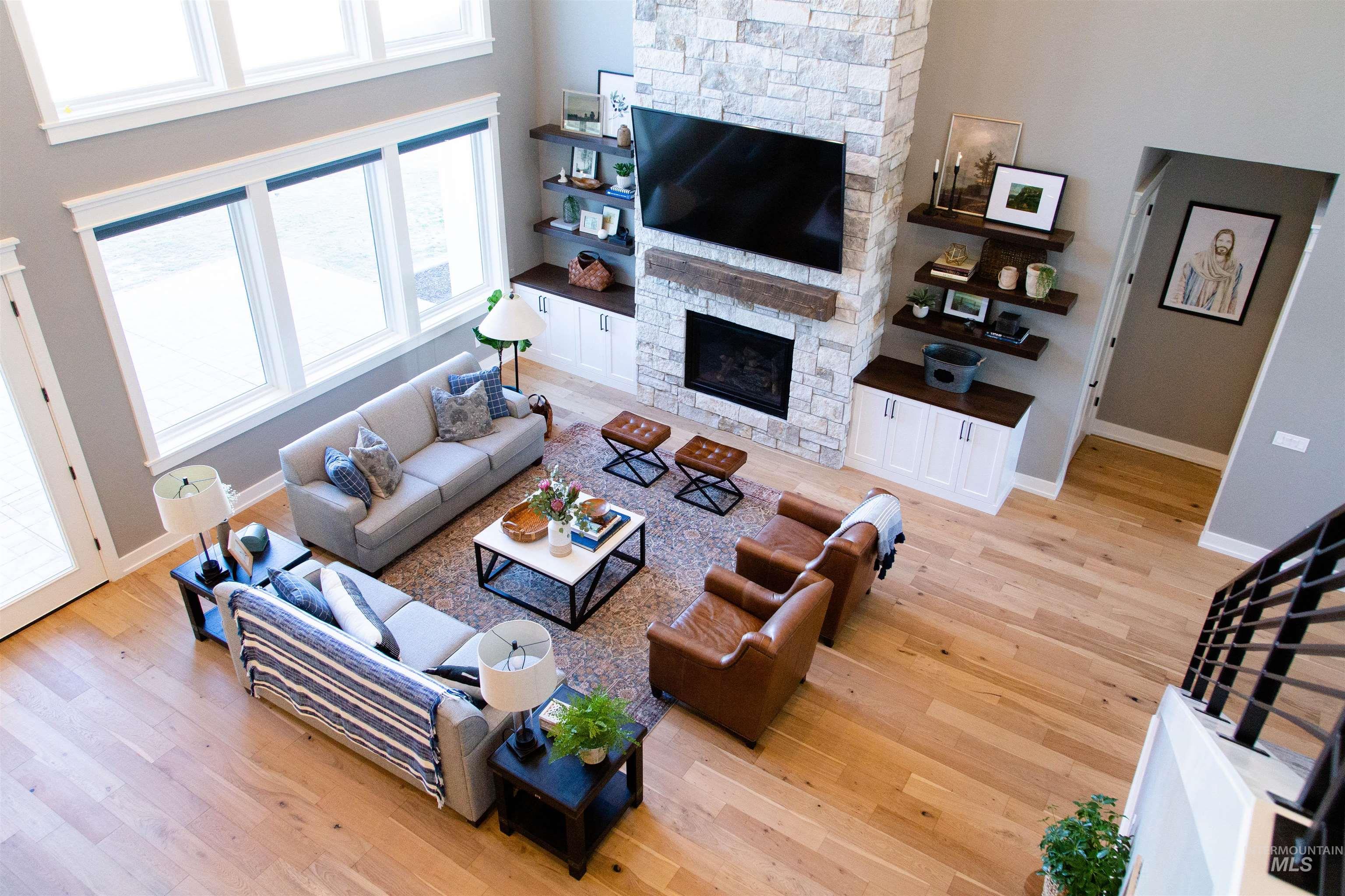 Living area featuring wood finished floors, a stone fireplace, and a high ceiling