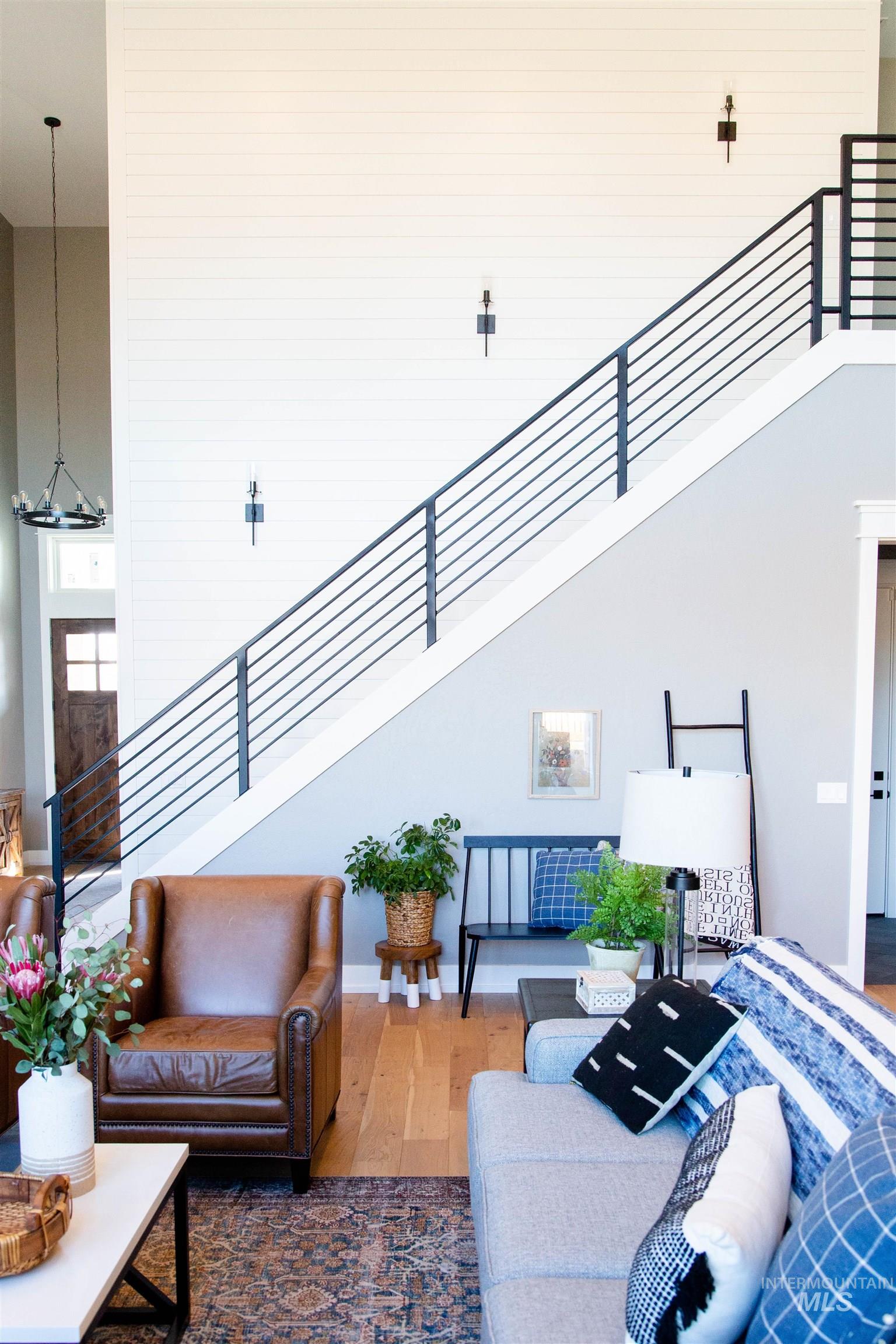Living room with wood finished floors, stairs, and a towering ceiling