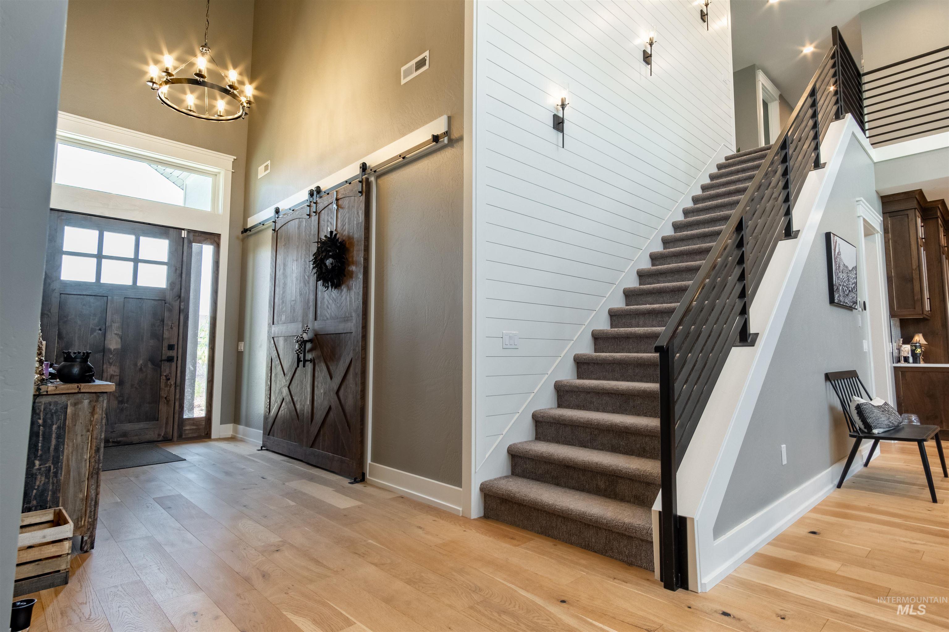 Foyer entrance featuring a high ceiling, stairway, light wood-type flooring, and a barn door