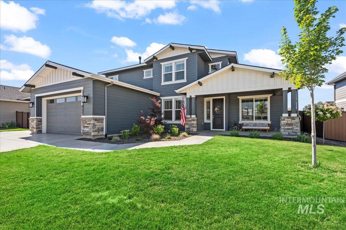 Craftsman house featuring a garage, driveway, board and batten siding, covered porch, and stone siding