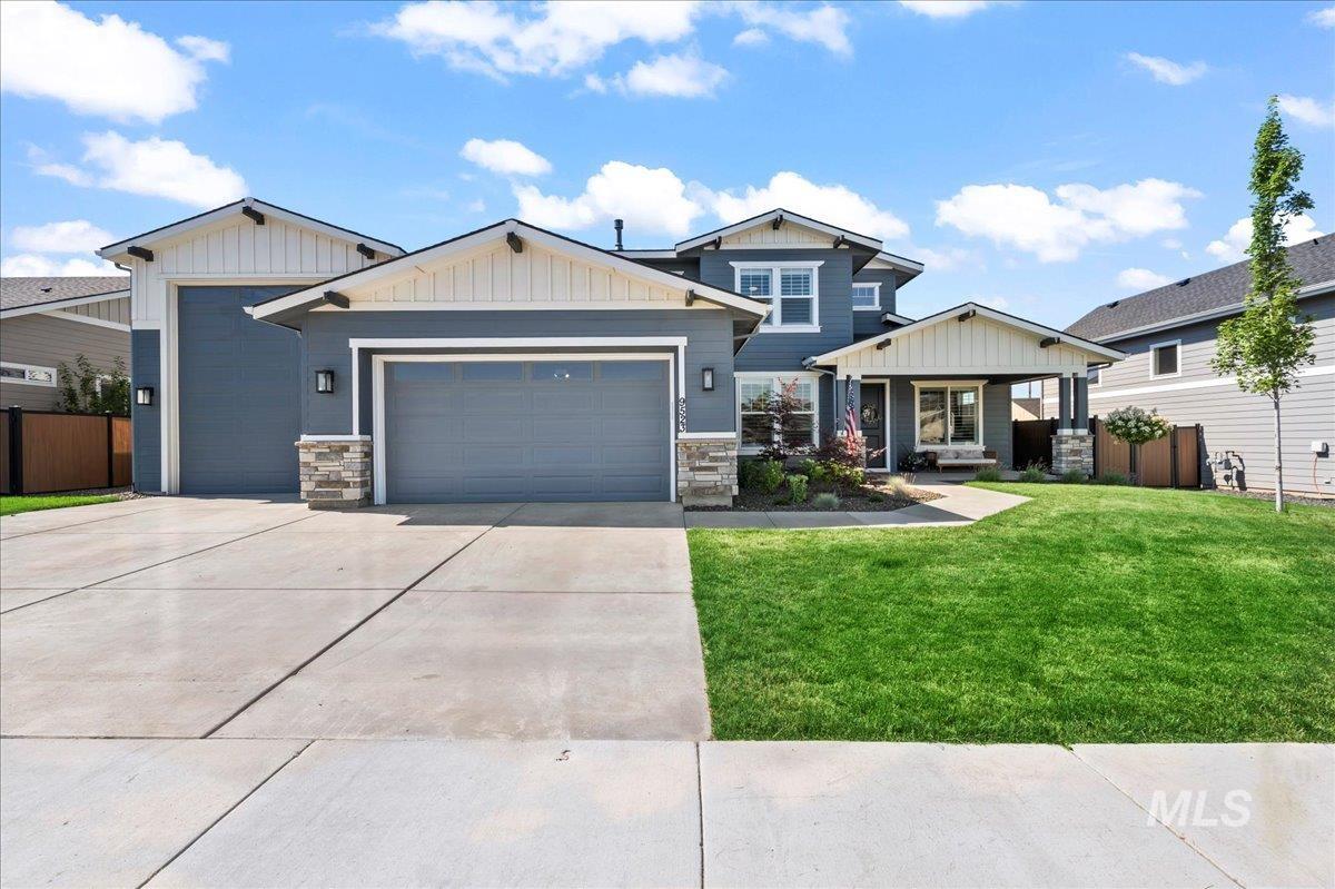 Craftsman house with an attached garage, concrete driveway, stone siding, and board and batten siding