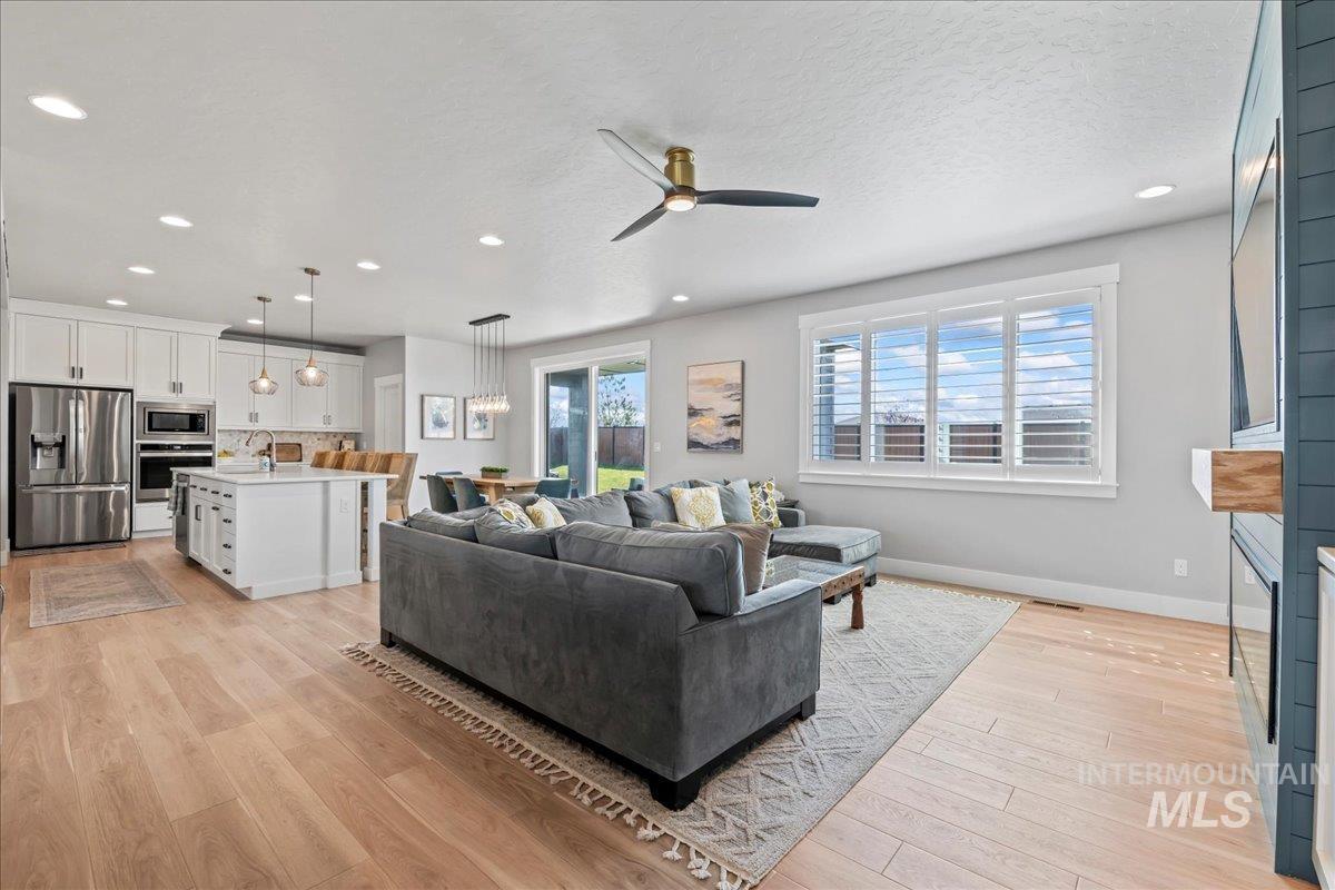 Living area featuring ceiling fan, light wood-type flooring, a fireplace, recessed lighting, and a textured ceiling