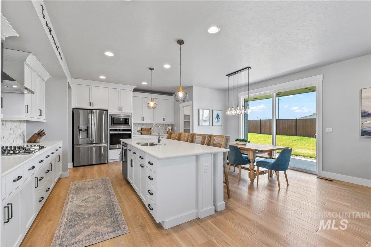 Kitchen with appliances with stainless steel finishes, decorative backsplash, light countertops, light wood-type flooring, and recessed lighting