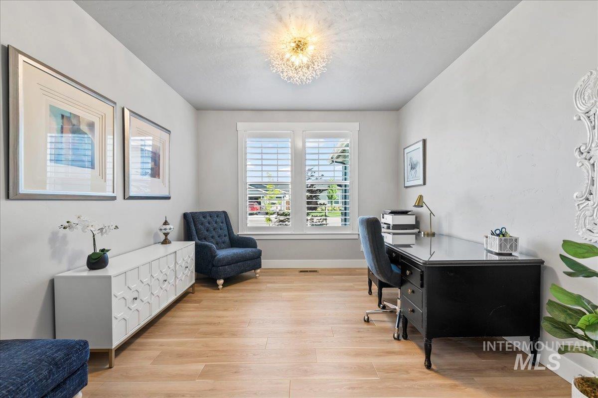 Office area featuring light wood-style flooring and a textured ceiling