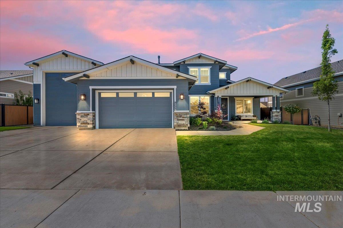 Craftsman-style home featuring a garage, stone siding, driveway, and board and batten siding