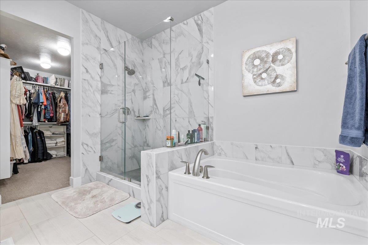 Full bathroom with a bath, a marble finish shower, a walk in closet, and tile patterned floors