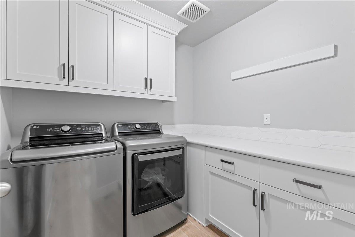 Laundry room featuring cabinet space, independent washer and dryer, and light wood finished floors