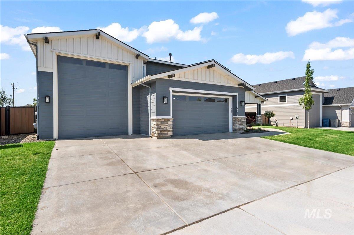 View of front of house featuring a garage, board and batten siding, driveway, and a front lawn