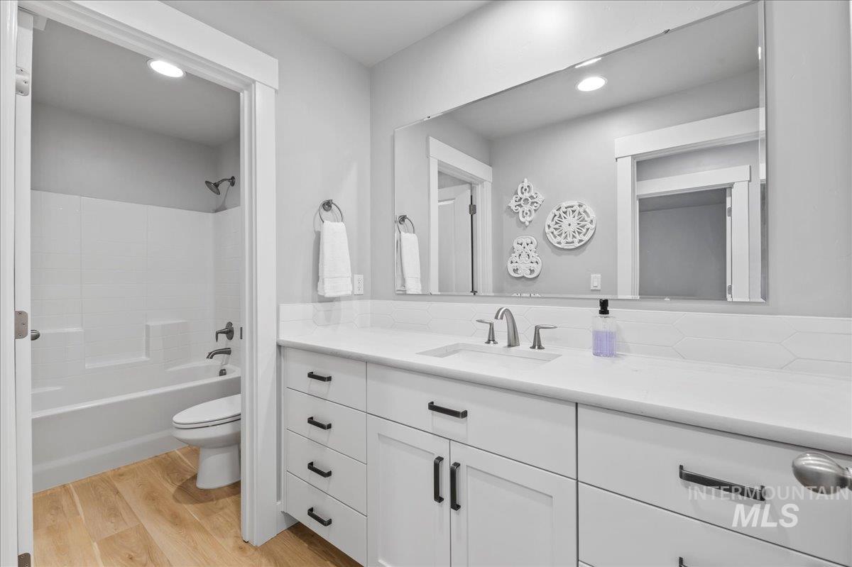 Full hall bathroom with vanity, wood finished floors,  shower combination, and recessed lighting