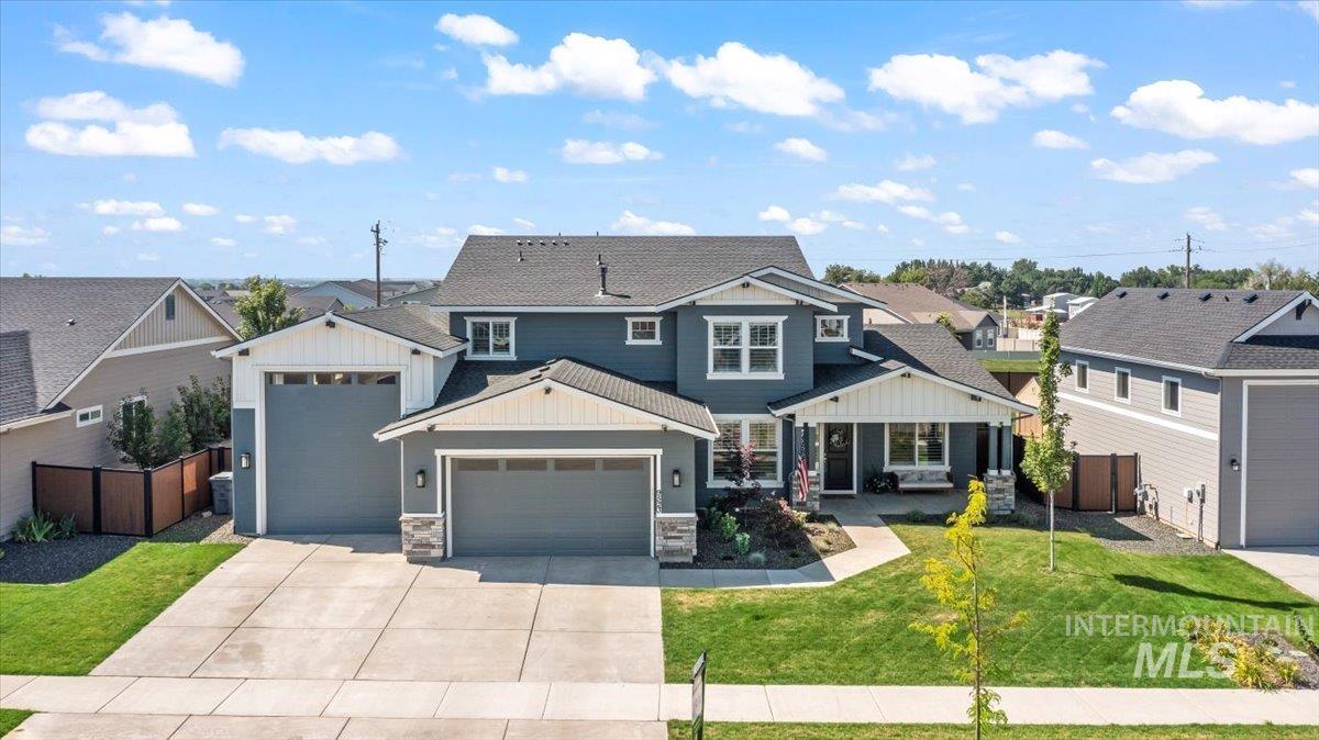 View of front of property with a garage, driveway, board and batten siding, stone siding, and a residential view