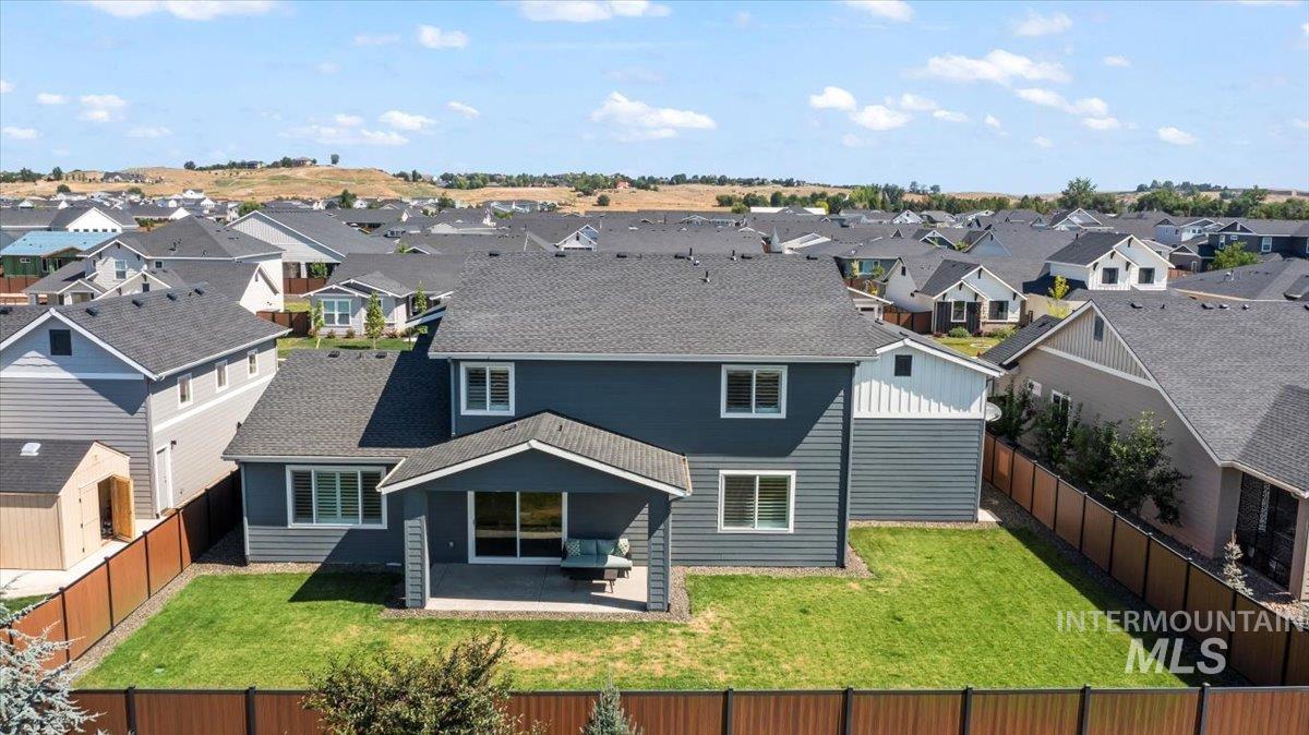 Rear view of property featuring a residential view, a patio, a fenced backyard, and roof with shingles