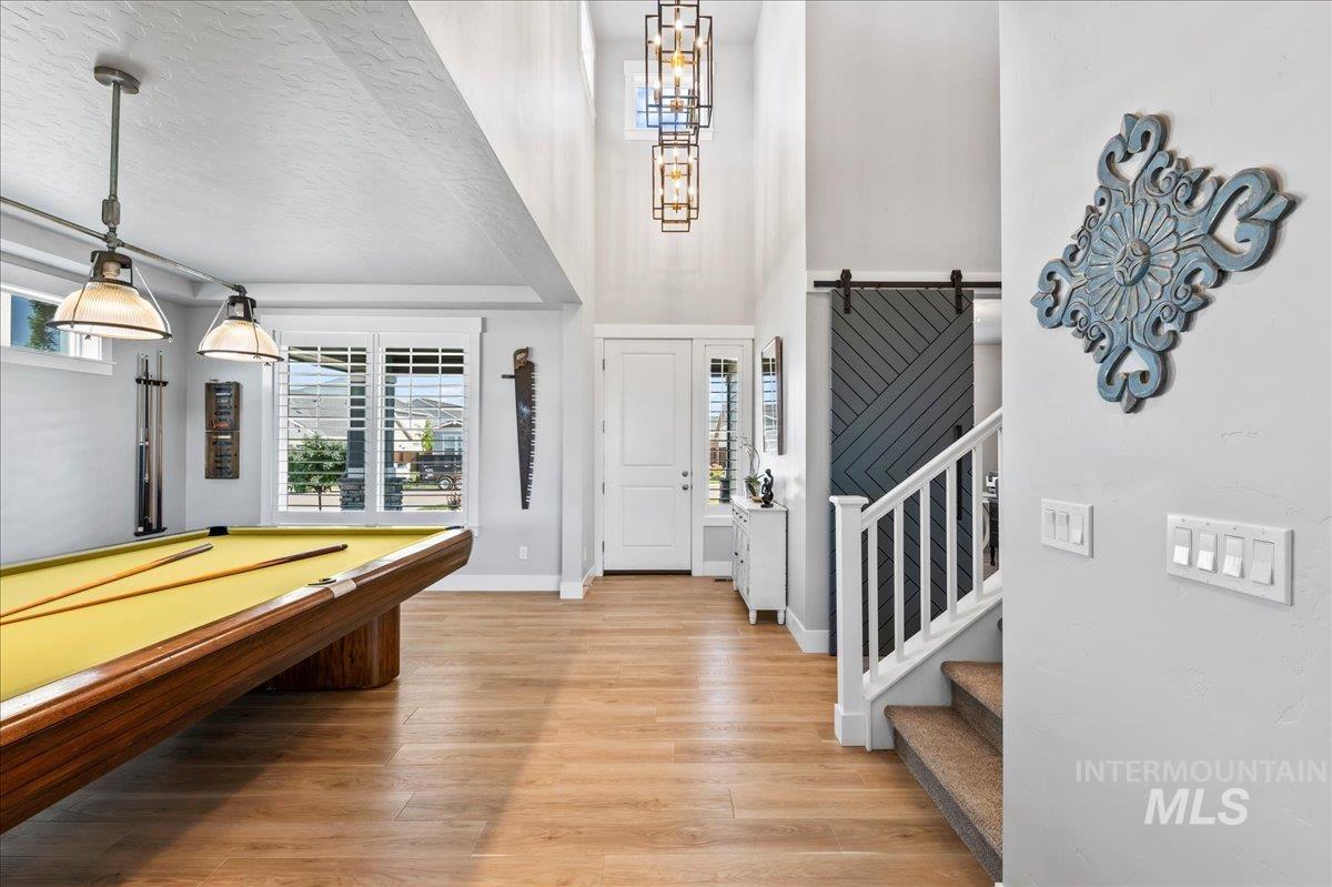 Foyer entrance with light wood-type flooring, stairs, a towering ceiling, and billiards