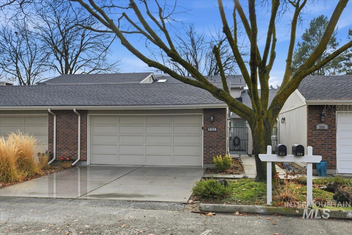 View of front of property with roof with shingles, brick siding, driveway, and a garage
