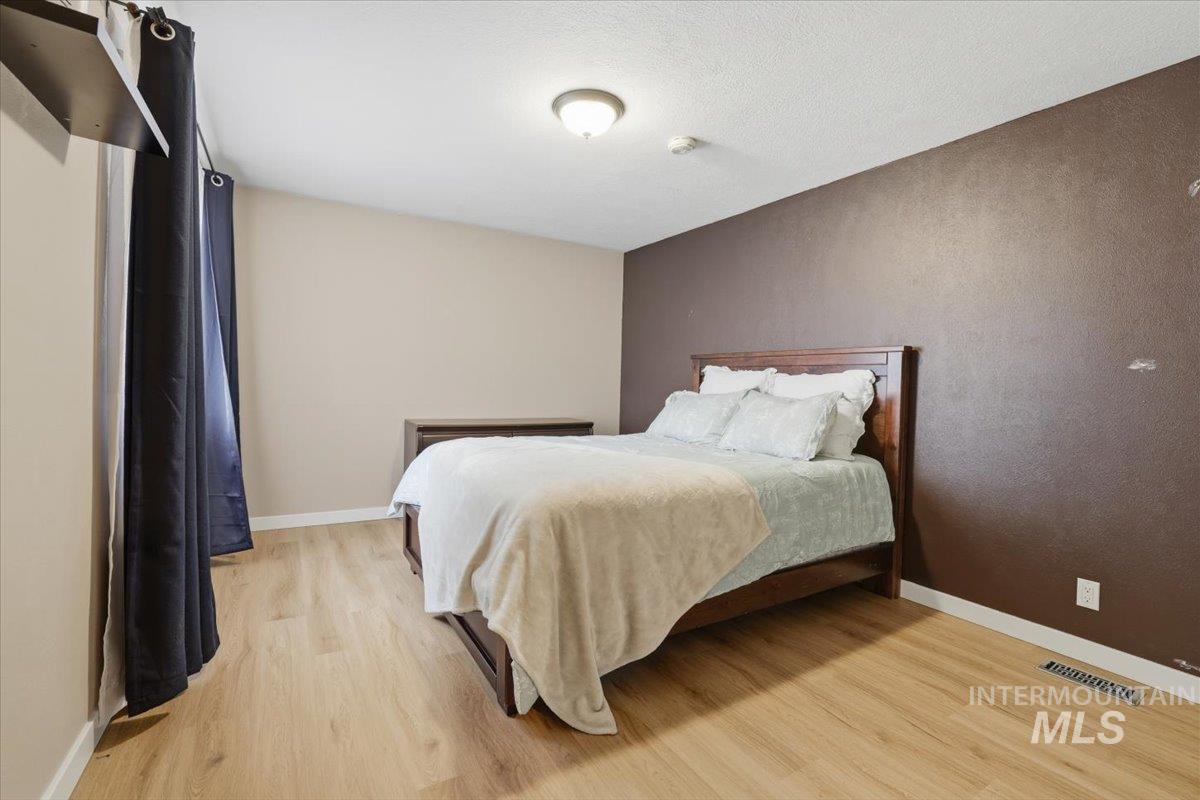 Bedroom with light wood-style floors and a textured wall