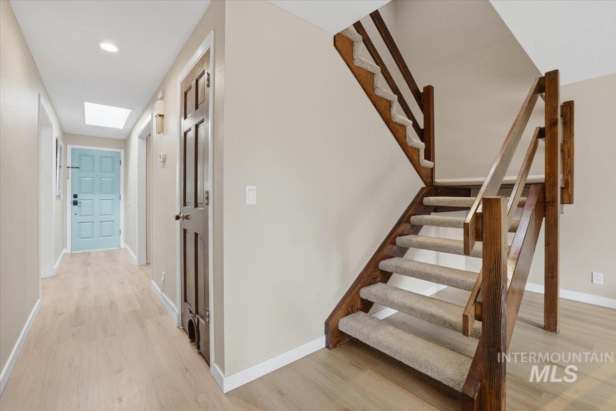 Staircase featuring wood finished floors, a skylight, and recessed lighting