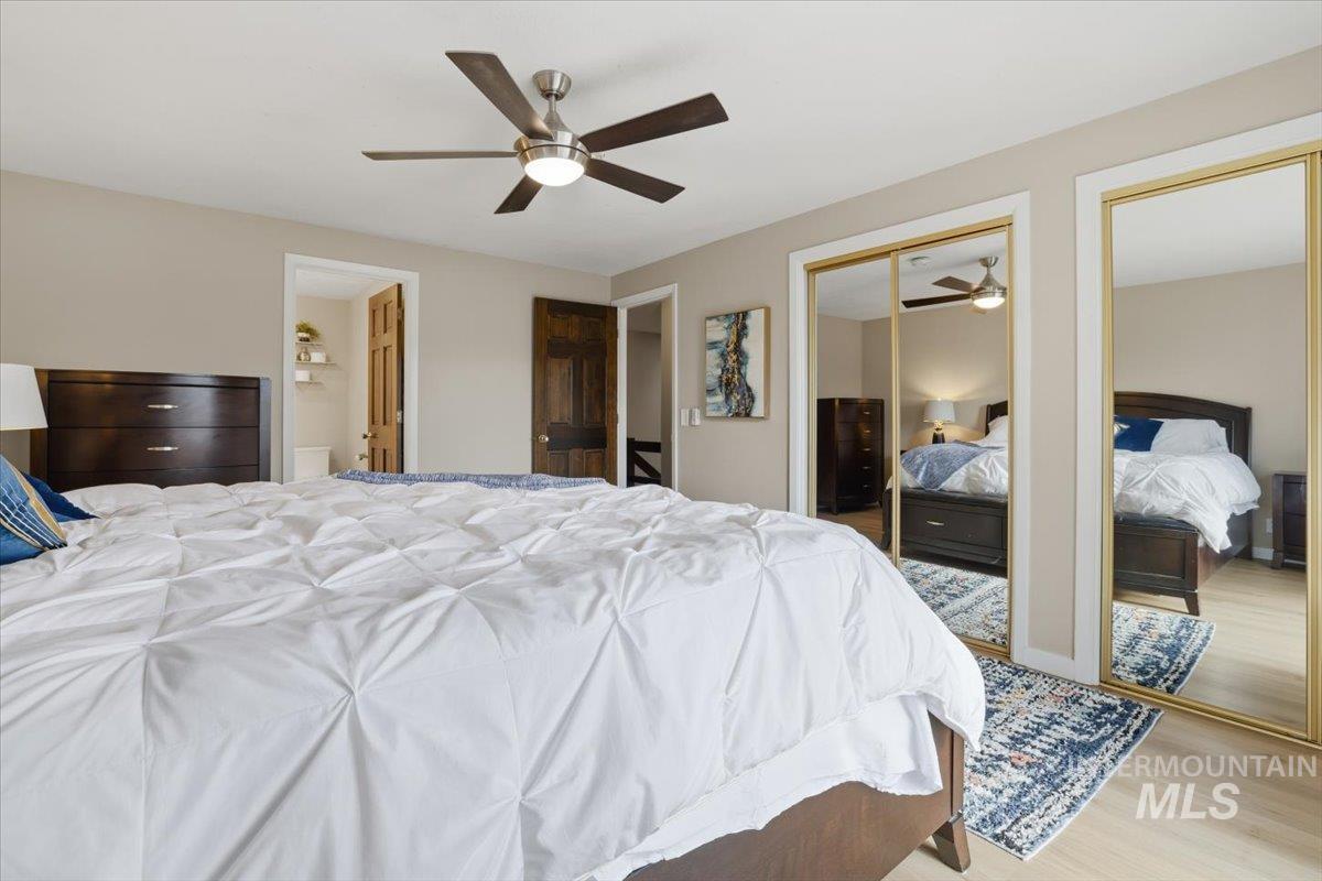 Bedroom featuring multiple closets, wood finished floors, and ceiling fan