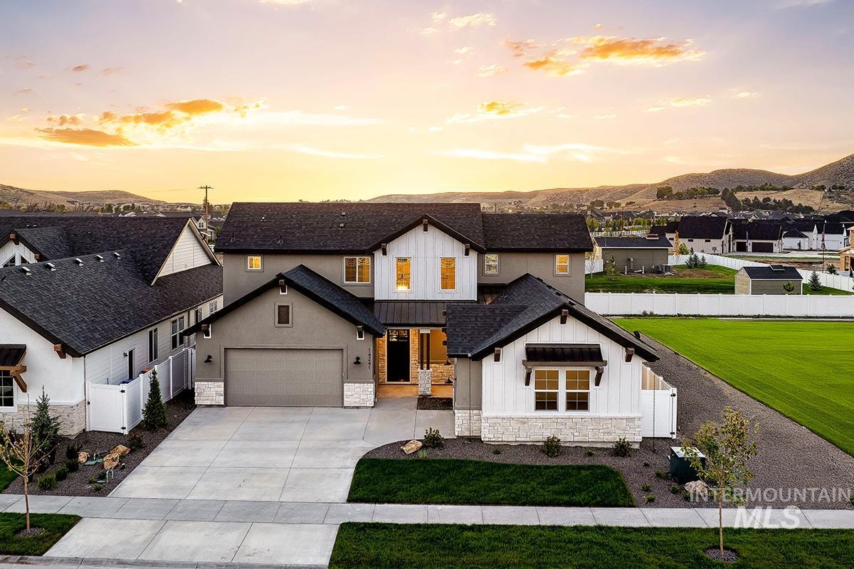 Modern farmhouse with board and batten siding, stone siding, concrete driveway, a shingled roof, and a mountain view