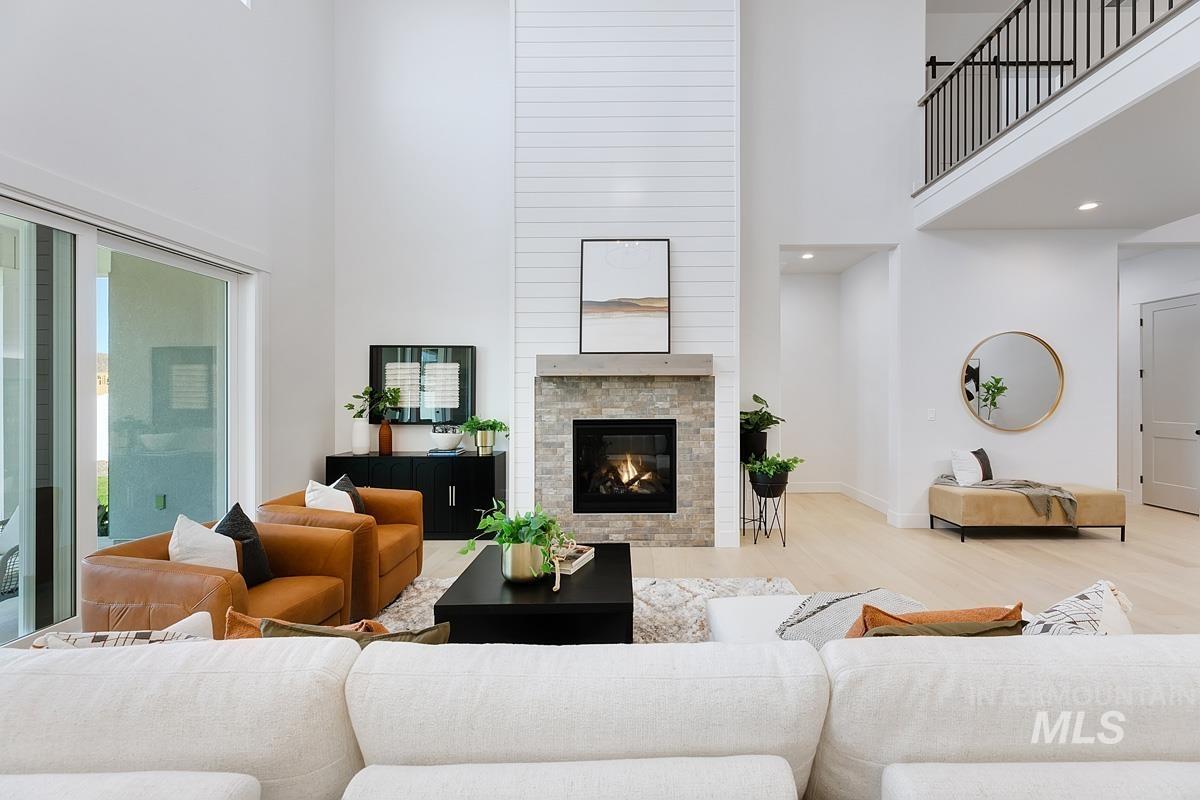Living area featuring a high ceiling, wood finished floors, and a glass covered fireplace
