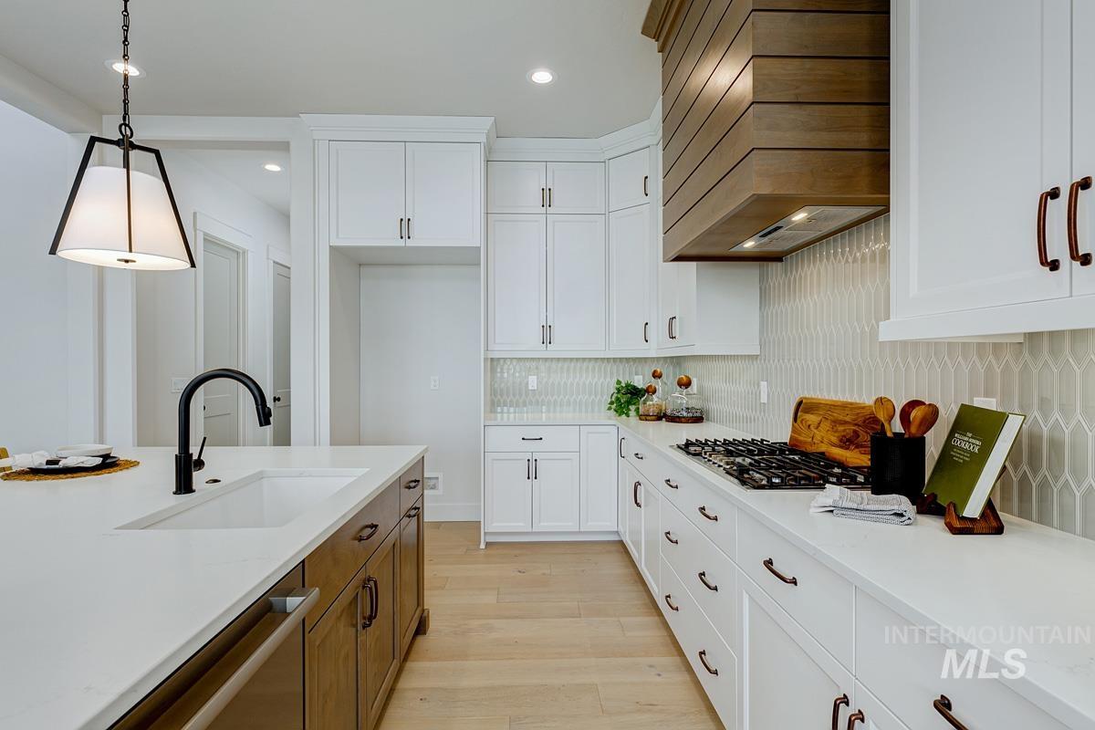 Kitchen with white cabinetry, decorative light fixtures, brown cabinets, and recessed lighting