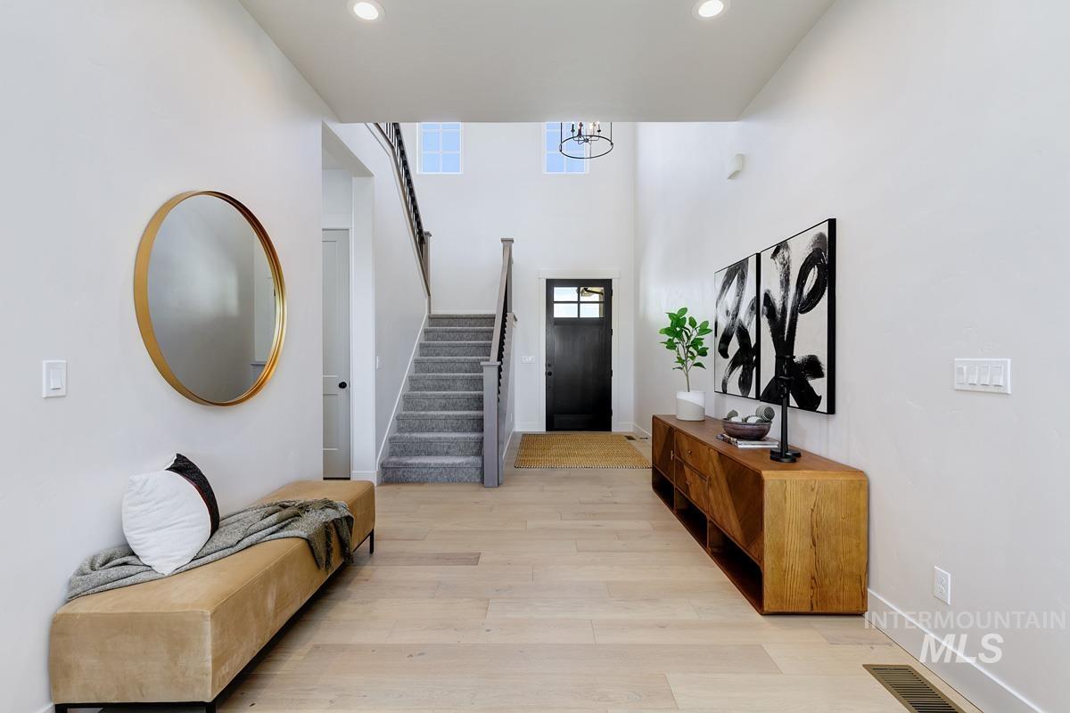 Entryway with light wood-style floors, stairway, a towering ceiling, and recessed lighting