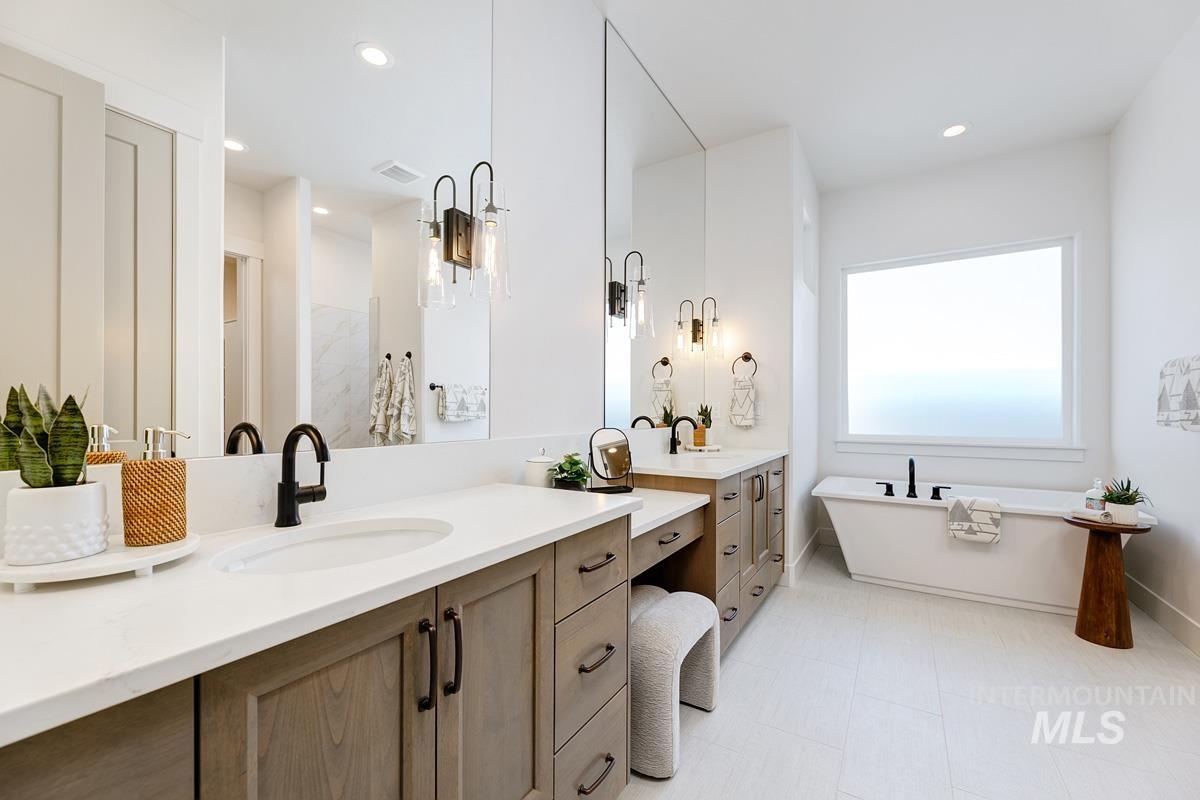 Full bath with two vanities, a freestanding tub, and recessed lighting