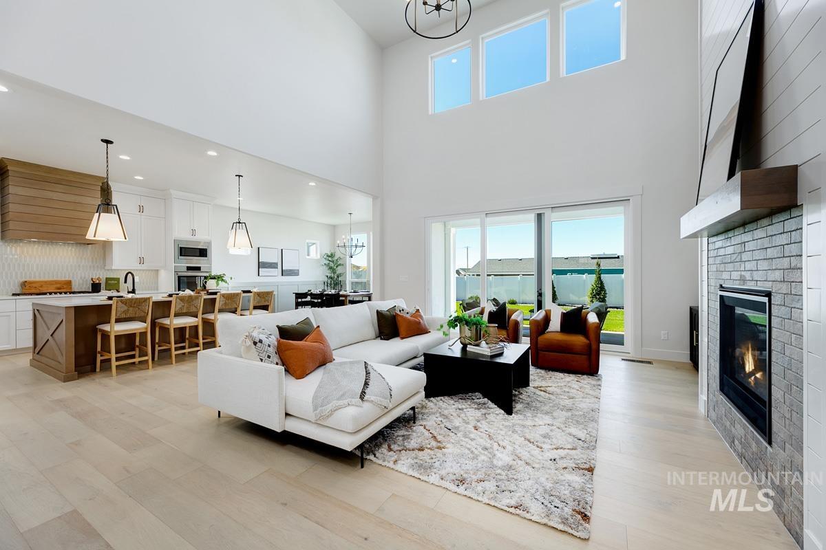Living area with a chandelier, light wood-type flooring, and a fireplace