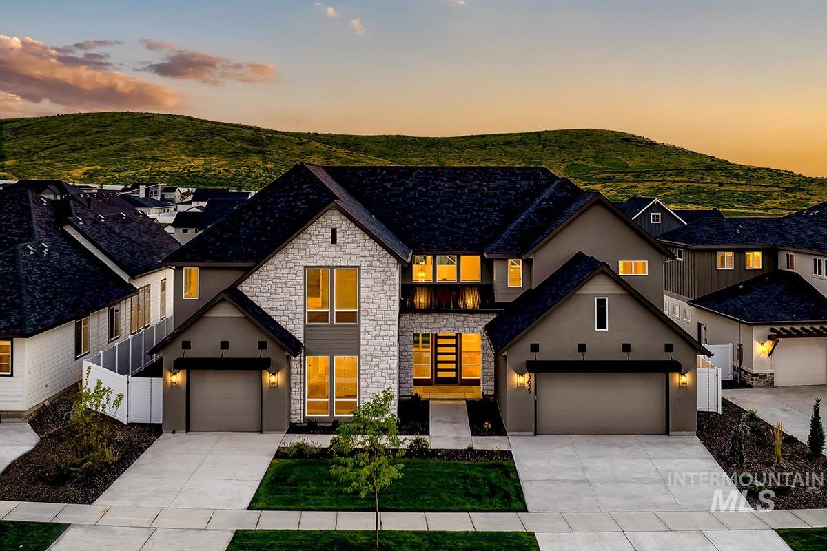 View of front of house with stone siding, driveway, a mountain view, stucco siding, and a garage