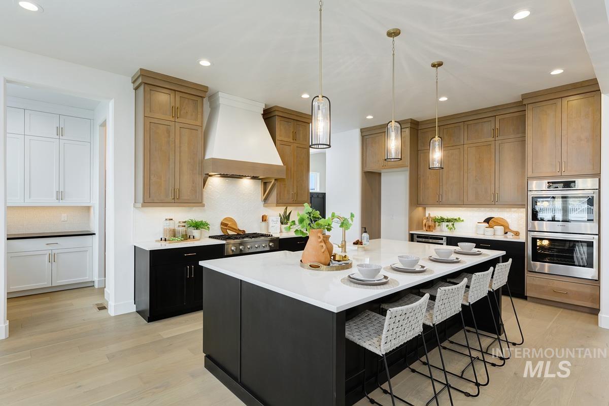 Kitchen featuring hanging light fixtures, tasteful backsplash, stainless steel appliances, custom exhaust hood, and dark cabinets