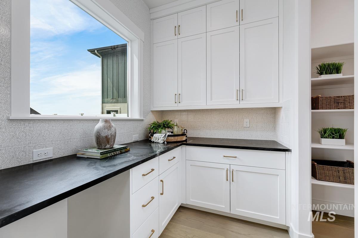 Kitchen featuring white cabinetry, light wood-type flooring, and backsplash