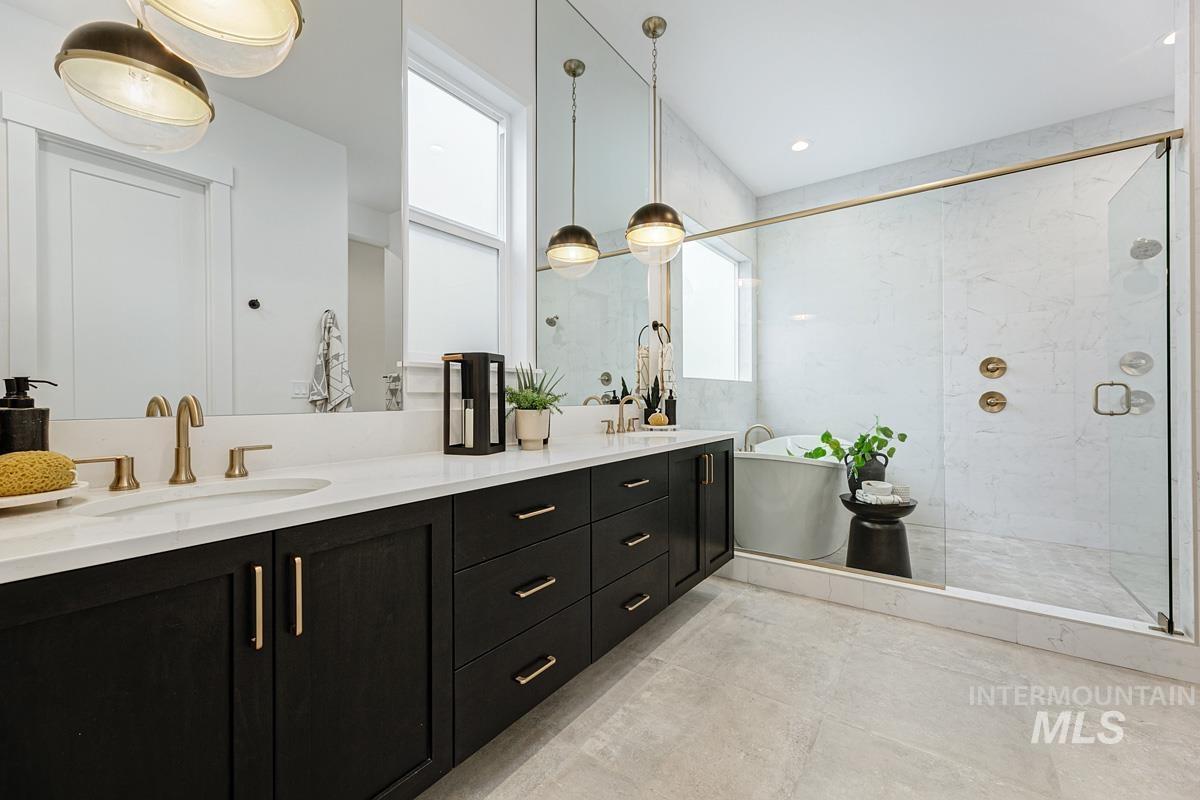 Full bath featuring a soaking tub, double vanity, and a marble finish shower