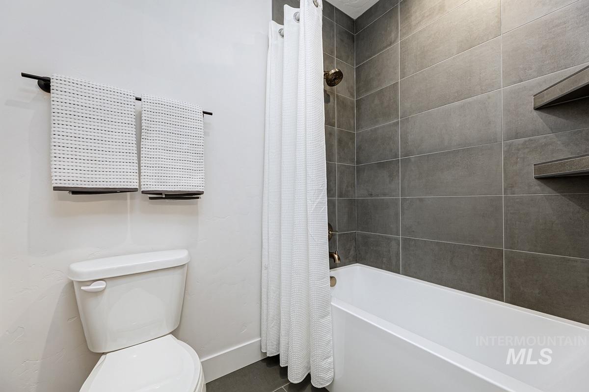 Full bath featuring shower / bathtub combination with curtain and toilet