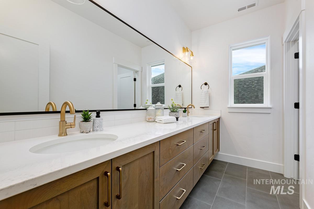 Full bath featuring double vanity and dark tile patterned floors