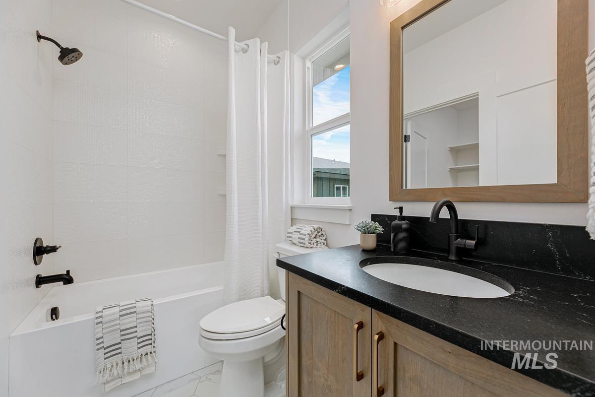 Bathroom featuring vanity, shower / tub combo with curtain, and marble finish floors