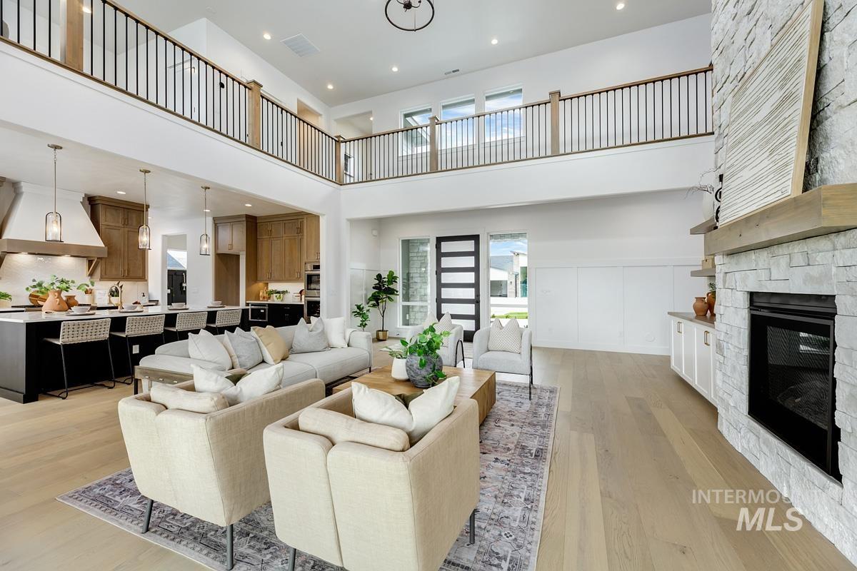 Living room with a fireplace, light wood finished floors, recessed lighting, and a towering ceiling