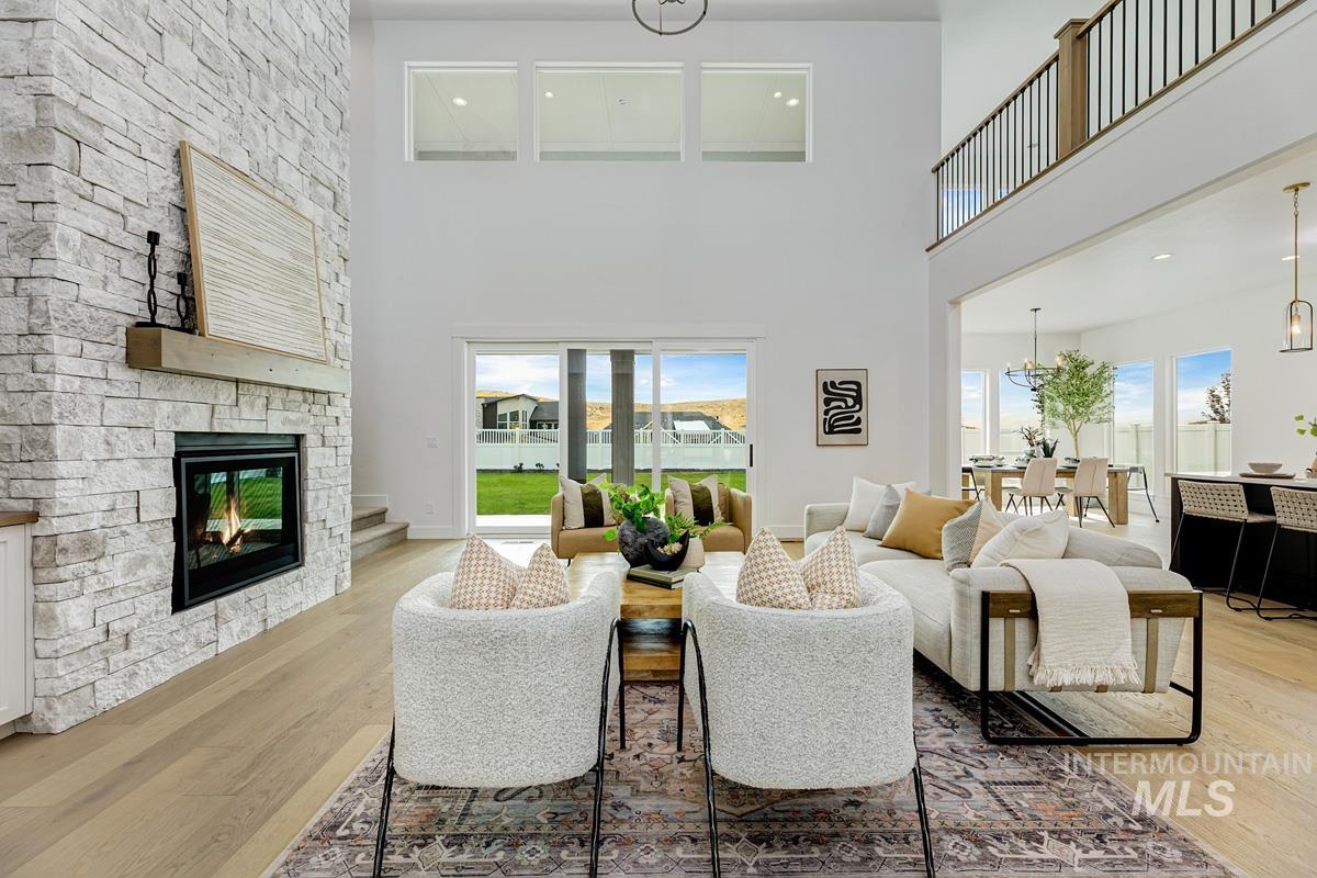 Living area featuring light wood-style floors, a high ceiling, healthy amount of natural light, recessed lighting, and a stone fireplace