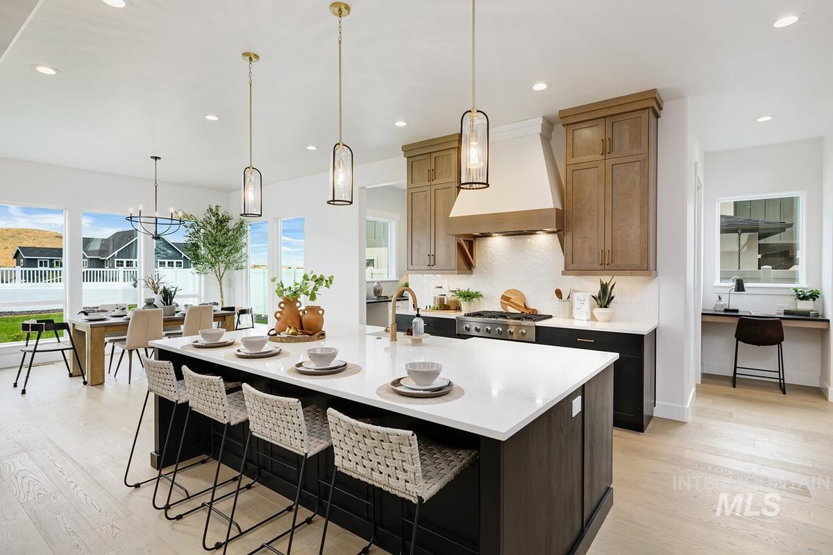 Kitchen with pendant lighting, custom range hood, recessed lighting, light wood-style floors, and a kitchen island with sink