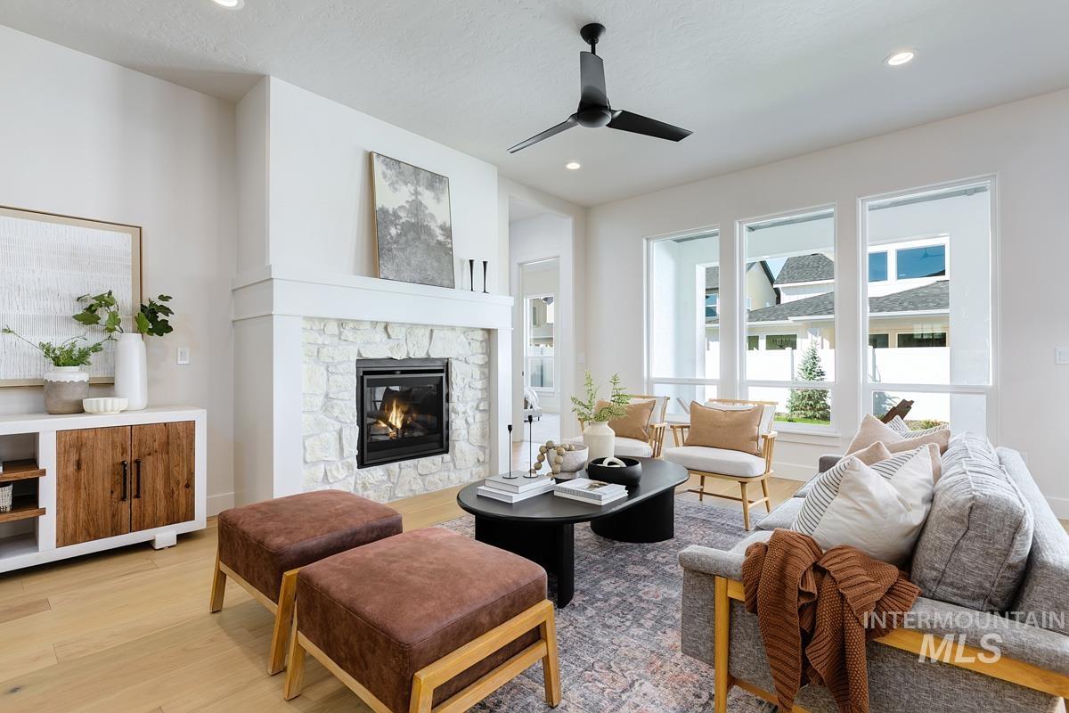 Living room with light wood-type flooring, a fireplace, a ceiling fan, and recessed lighting