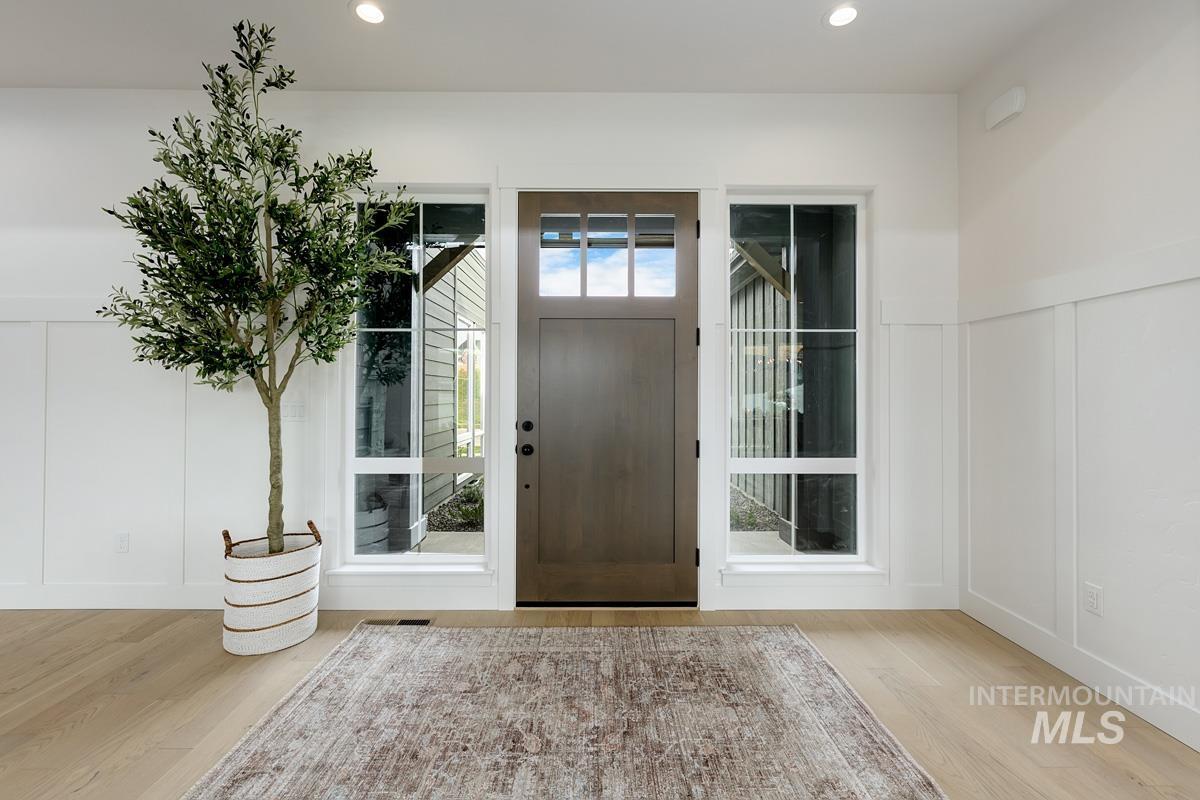 Entryway with a decorative wall, light wood-type flooring, recessed lighting, and a wainscoted wall