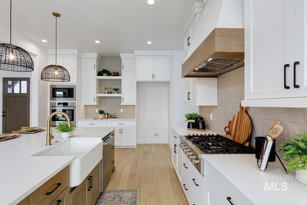 Kitchen with premium range hood, white cabinets, hanging light fixtures, and recessed lighting