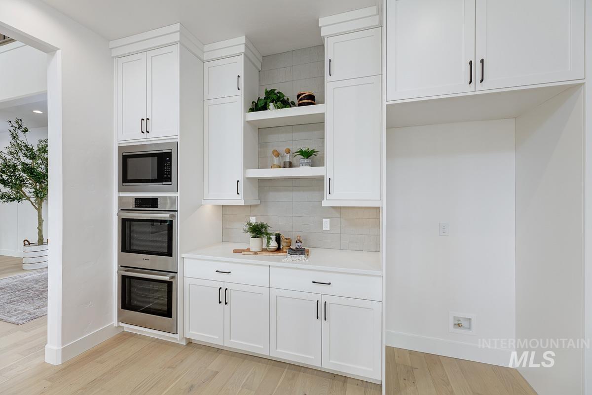 Kitchen featuring open shelves, white cabinetry, and backsplash