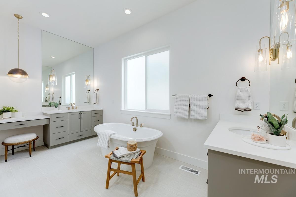 Full bath featuring two vanities, a freestanding bath, and recessed lighting