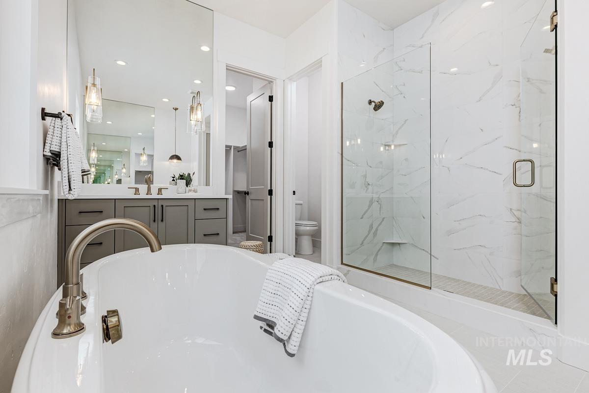 Bathroom featuring vanity, a soaking tub, a marble finish shower, and recessed lighting