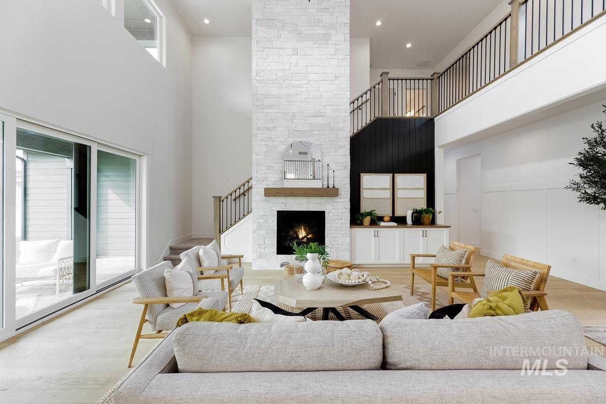 Living room featuring a high ceiling, stairway, a fireplace, and wood finished floors