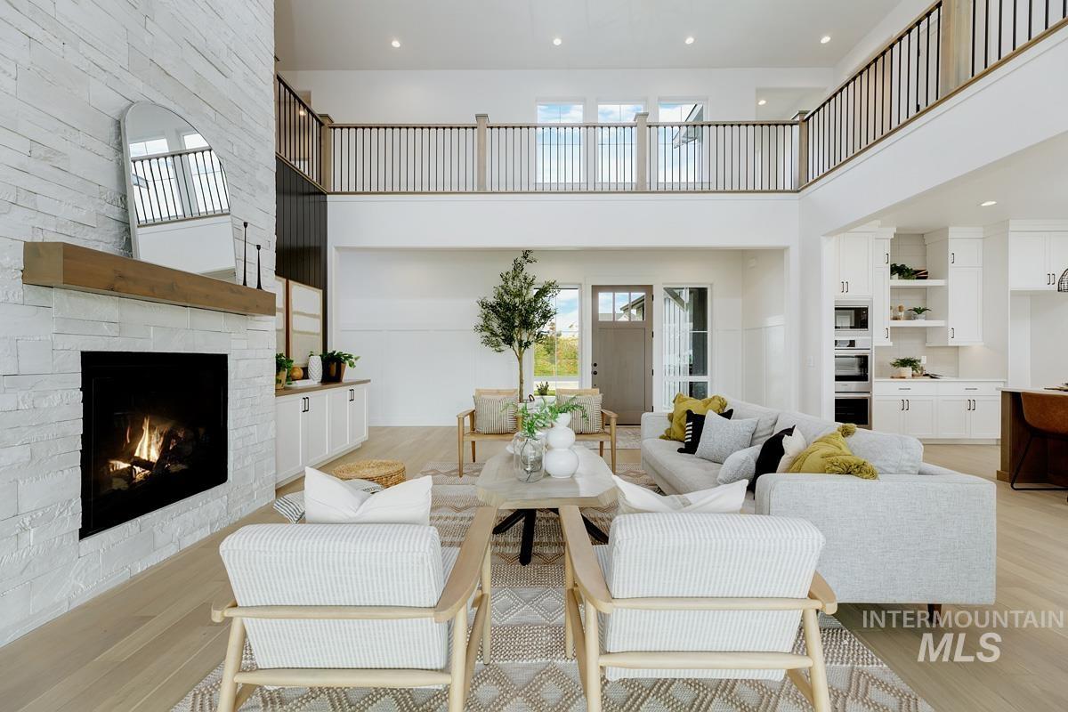 Living area with light wood-style floors, a stone fireplace, a high ceiling, recessed lighting, and built in features