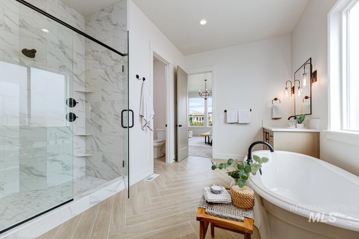Full bathroom featuring vanity, a marble finish shower, a freestanding tub, recessed lighting, and a chandelier