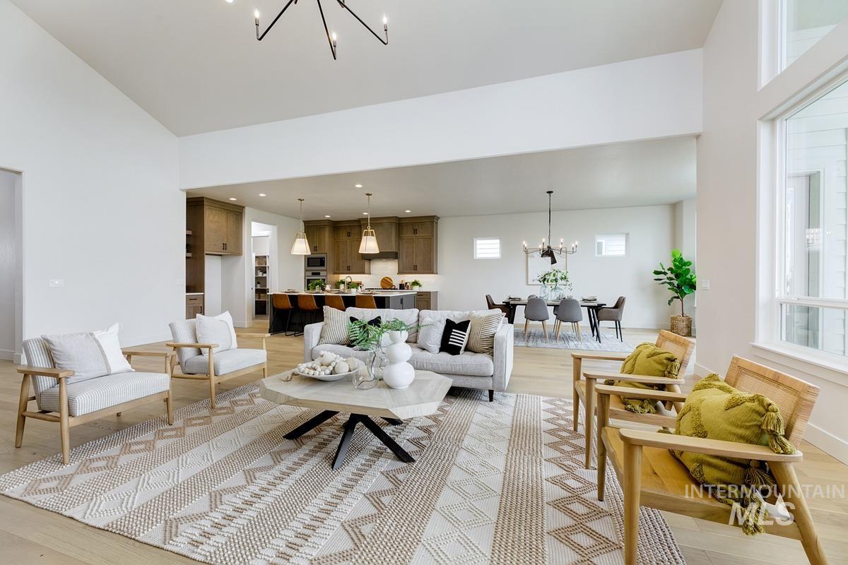 Living room with a chandelier, light wood-style flooring, and a towering ceiling