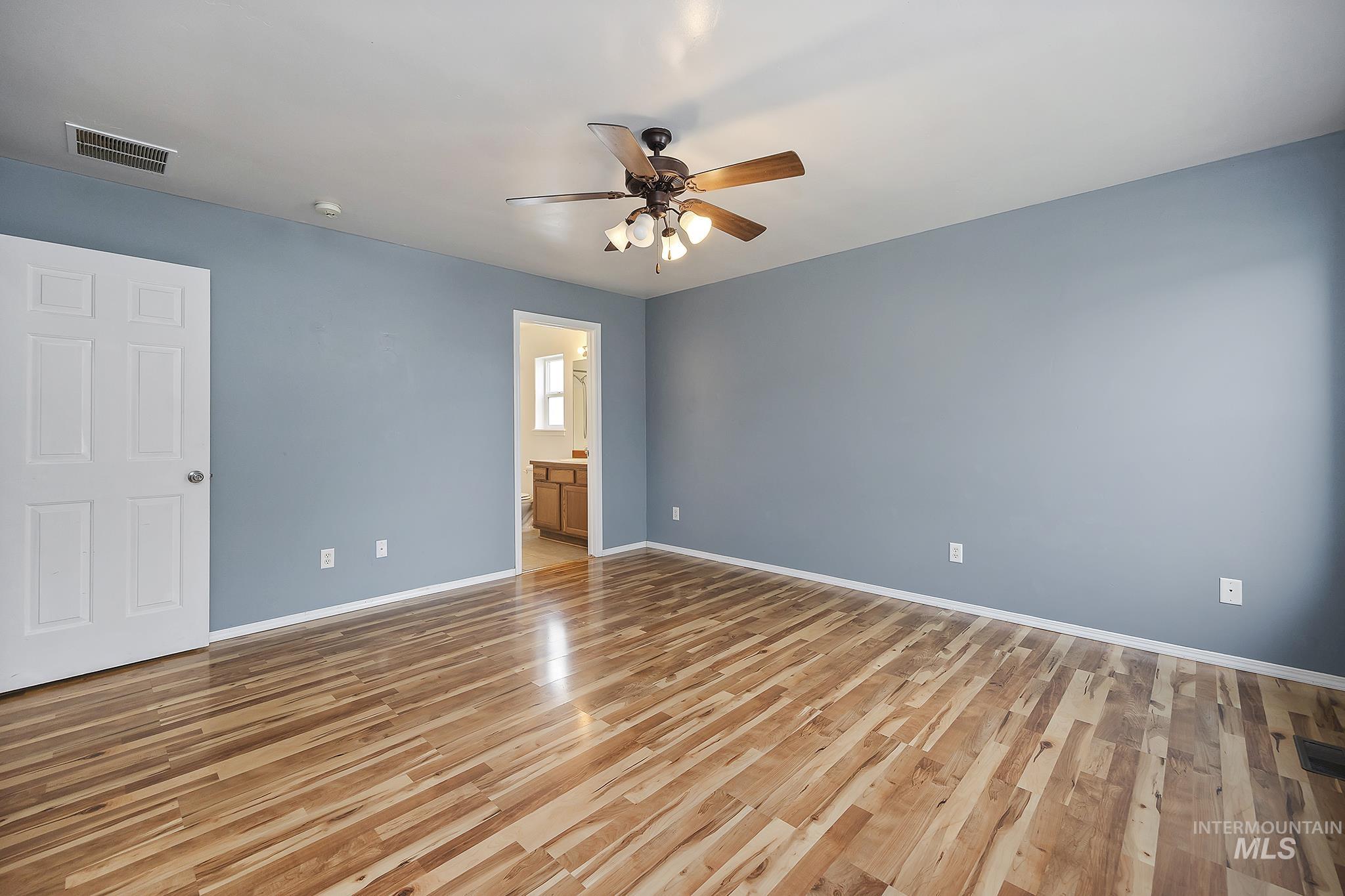 Unfurnished bedroom with light wood-style flooring, a ceiling fan, and ensuite bathroom