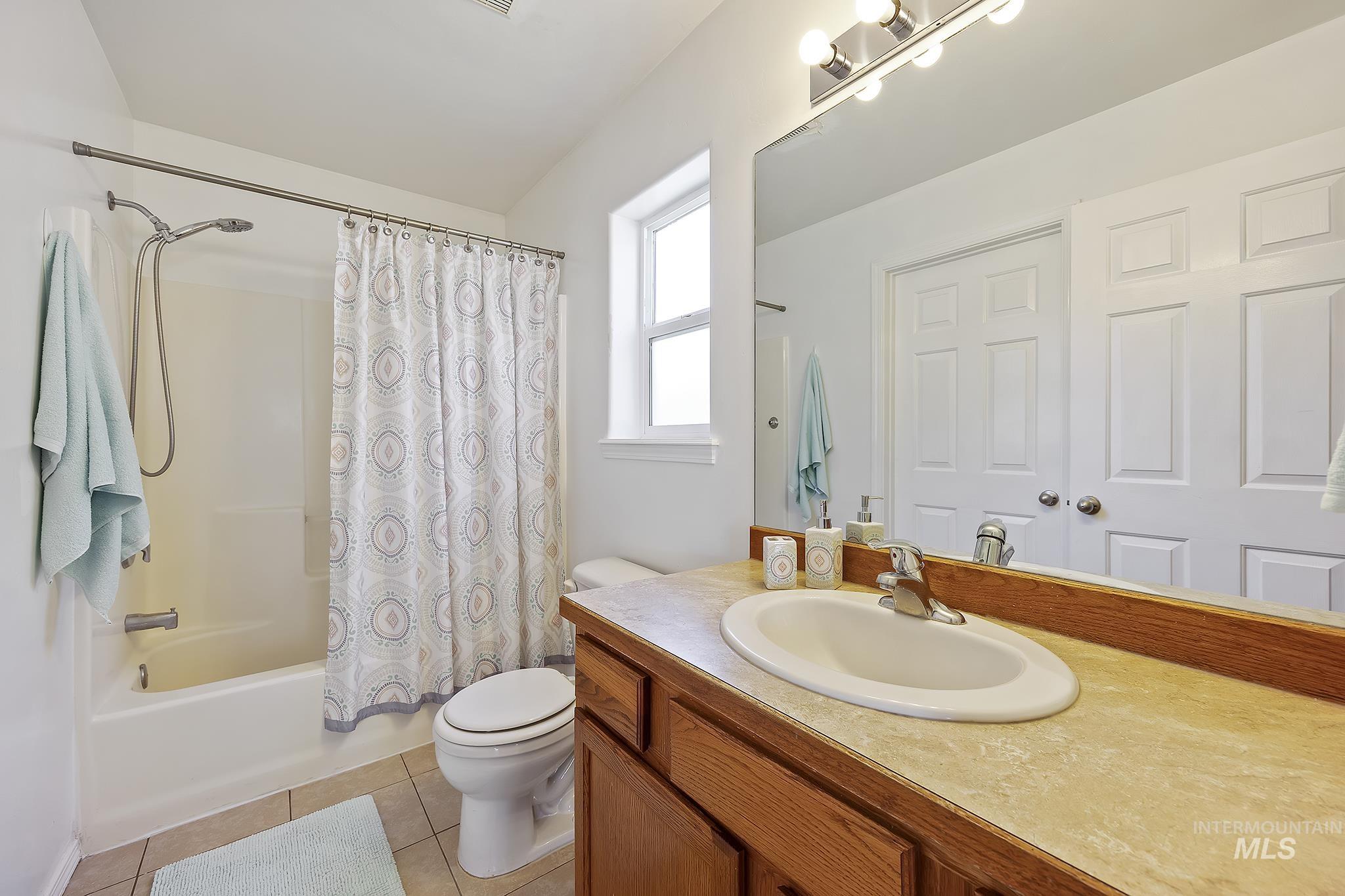 Full bathroom featuring shower / bath combo, vanity, and light tile patterned flooring